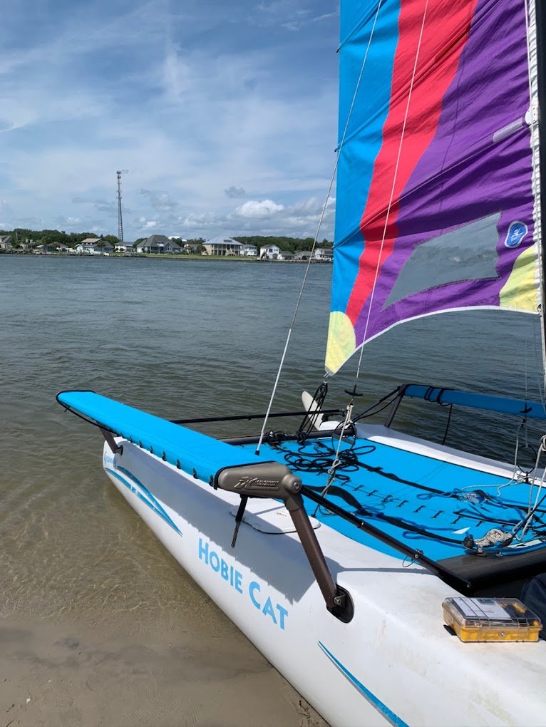 Detail of the Hobie Cat hull and sail on calm coastal water